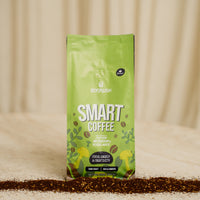 Green coffee bag labeled 'Smart Coffee' on a beige background with scattered coffee grounds.